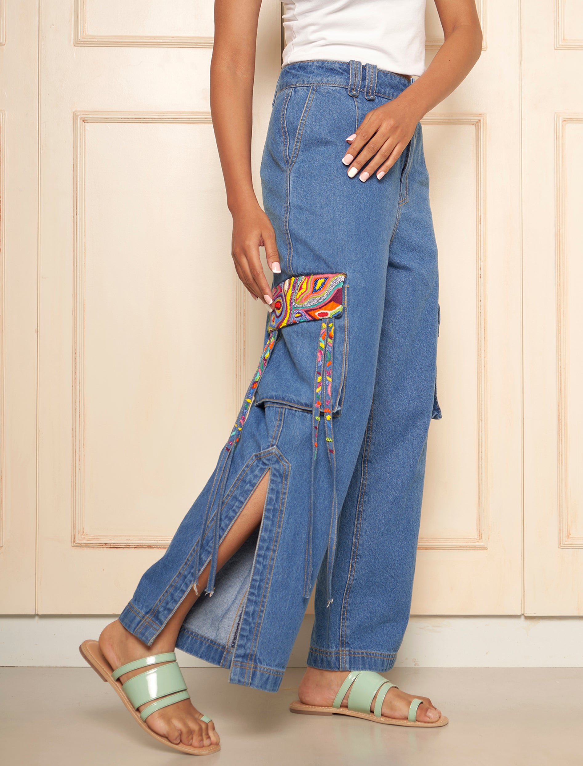 A pair of denim cargo pants with side slits and multicolor embroidered flap detail