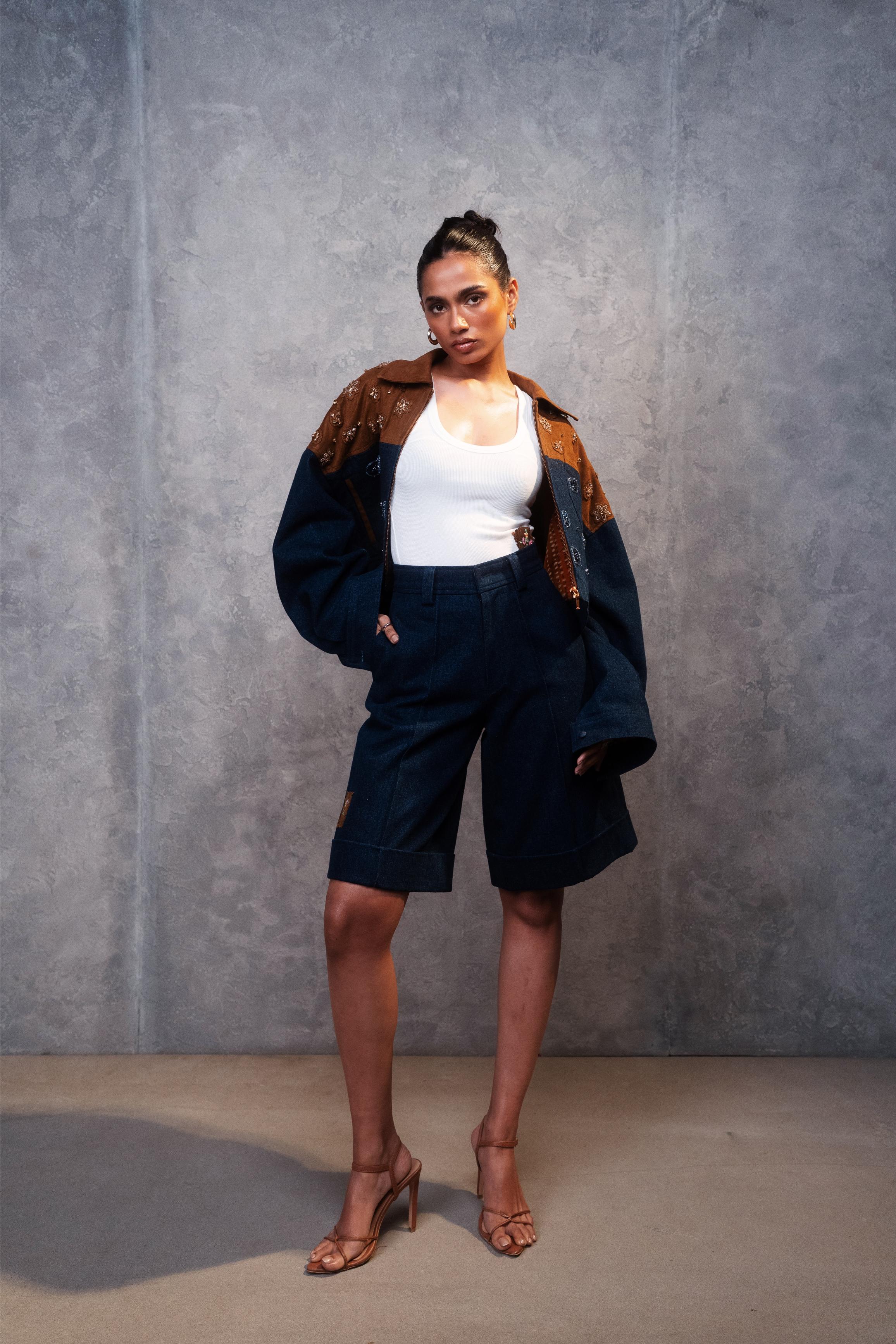 Woman wearing a white top, navy shorts, and a dark jacket